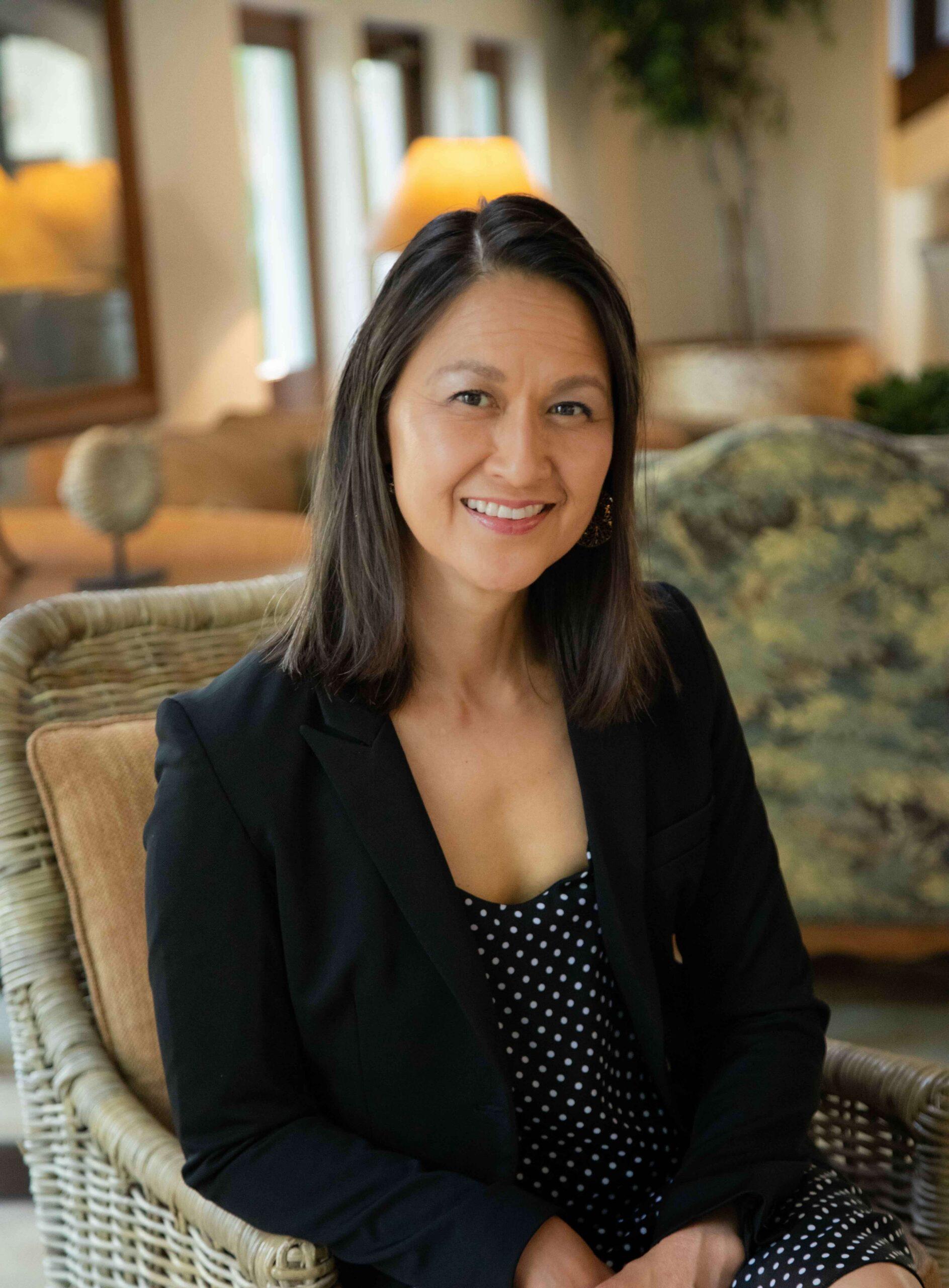 May Bugenhagen, founder of Two Asian Matchmakers, seated and smiling.