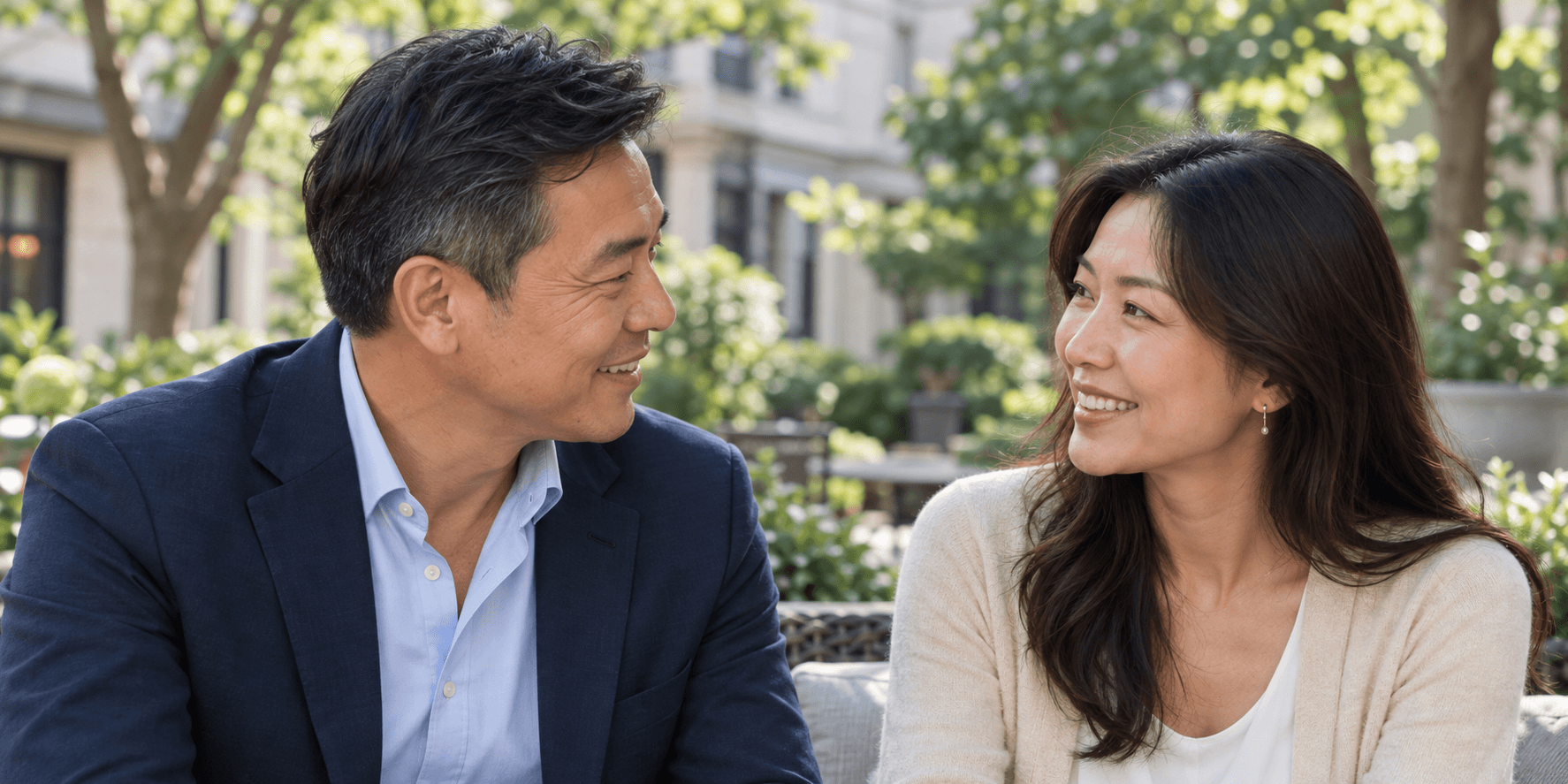 Chinese man and woman smiling at each other in a leafy courtyard